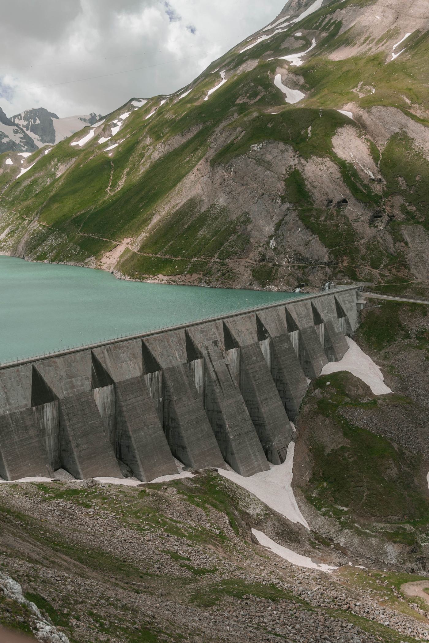 Buttress dam holding back a turquoise alpine reservoir