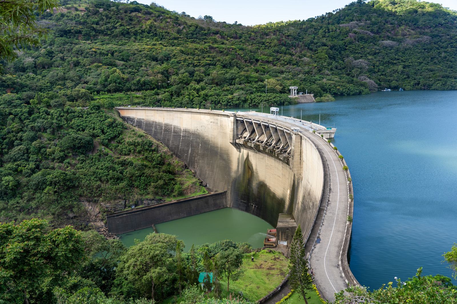 Curved hydroelectric dam wall beside a forested reservoir